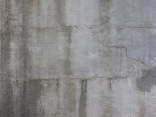 A gray concrete wall with cracks and dark stains from dampness. Texture not seamless