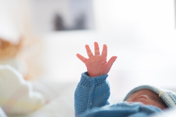 a newborn in his cradle raises his hand