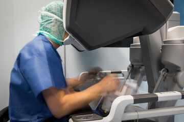 a surgeon manipulates the controls of a robot that operates a patient