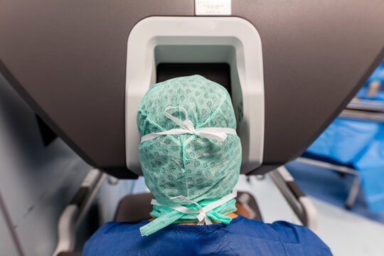 a surgeon is in front of the controls of a robot in the operating room