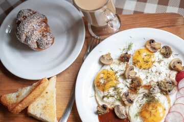 Breakfast with coffee, fried eggs, vegitables, croissant, toast.