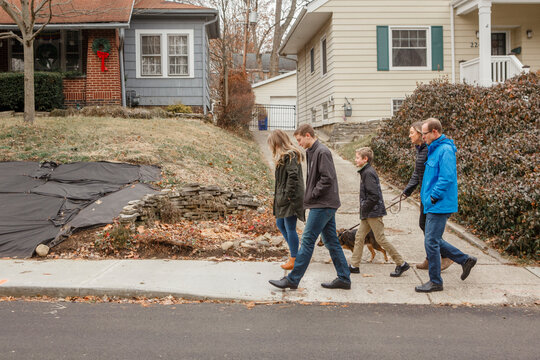 A family walk together with dog through suburban neighborhood