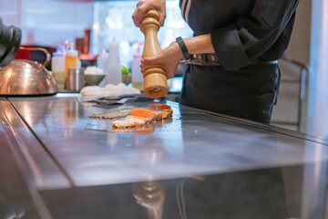 Hand of Chef cooking salmon steak