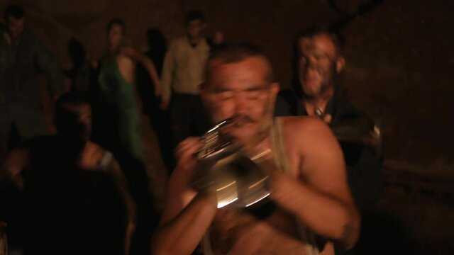 Crazy orchestra playing. Funny musicians play underground in a cave at night. Crazy people play musical instruments and dance funny dances in the cave. Funny bass guitarist, tubist, trumpeter, drummer