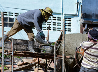 Construction workers pouring cement, sandstone and water into the mortar mixer.