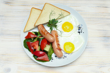 Breakfast plate top view, scrambled eggs with toast and sausages on white plate