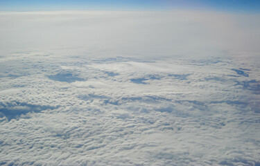 Clouds view from the airplane window. The sky is with cumulus clouds. Beautiful background. Travels. Flying over the cloud. To fly