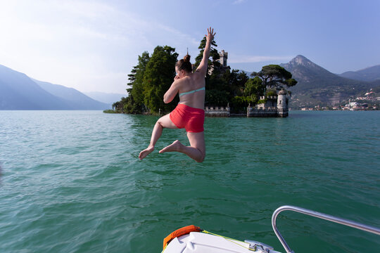 A girl jumping off of a boat into a lake in Italy.