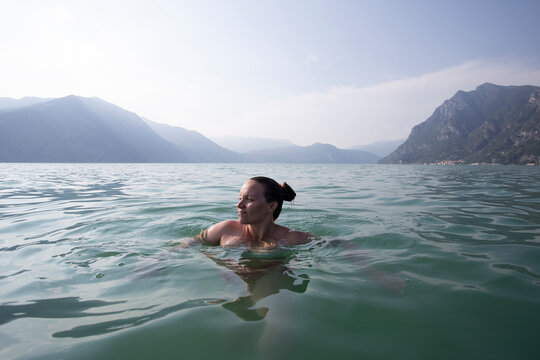 A young woman floating in the middle of a lake in Italy