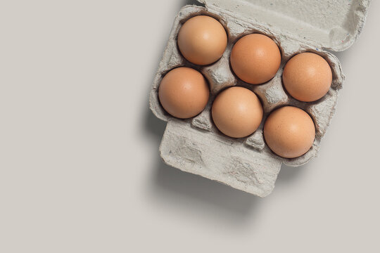 photo or picture of 6 eggs in a box, eggs in a photo with a brown background