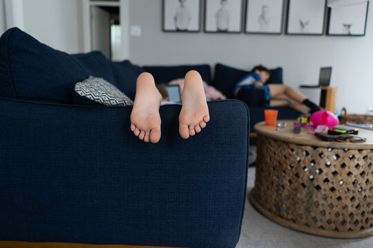 feet and toes of child laying on couch with brother in background