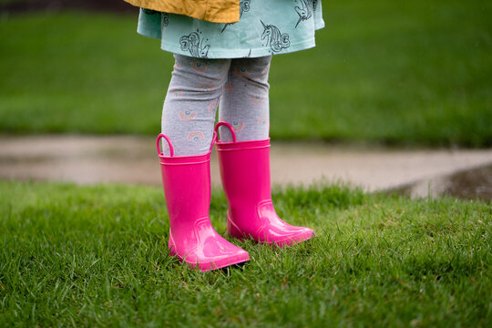 legs view of little girl in bright pink rain boots in yard