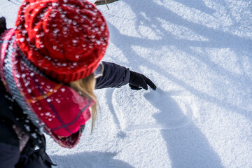horizontal top view of woman hand wearing a red leather glove and drawing a heart shape in the snow with the index finger, concept for love, winter time