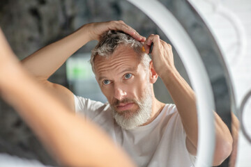 Man combing at home in front of mirror