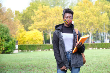University female african student wearing protective face mask outside on campus. New normal in college.