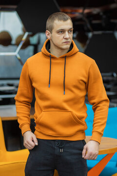 Handsome attractive European muscular man in orange hoodie