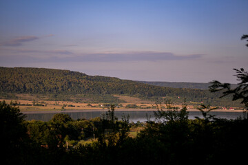 spring landscape with forest near the lake at sunset. cultivated fields