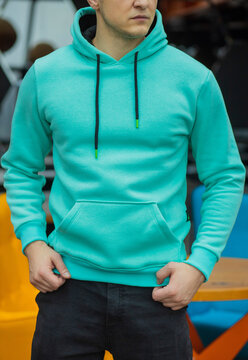 Handsome attractive European muscular man in turquoise hoodie