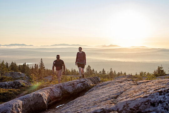 Two people walk along Appalachian Trail on summit of Maine Mountain.