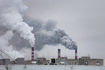 Fototapeta na wymiar industrial chimneys with heavy smoke causing air pollution on the gray smoky sky background