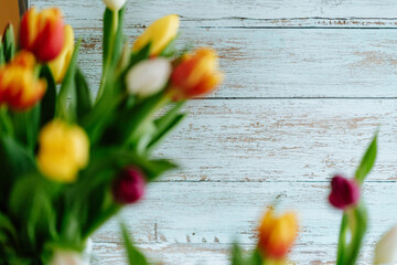Wooden background with colorful tulips out of focus in the foreground, Still life, text space