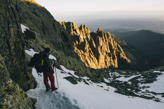 Young man assessing hike downhill situation during sunset at Gredos, Avila, Spain