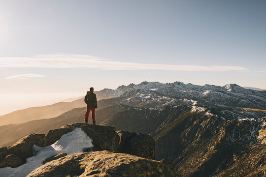 Young man admiring rugged snowcapped mountain landscape at sunset, Gredos, Spain