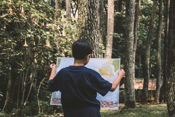 A boy standing in the jungle with holding map for navigation. Kid looking for route, adventurous child