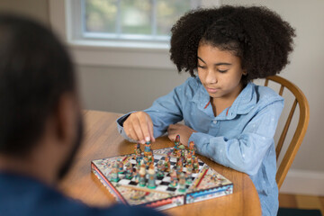 African America ten year-old girl playing board game with father