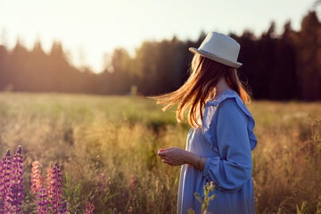 A girl in a field  standing in the rays of the setting sun