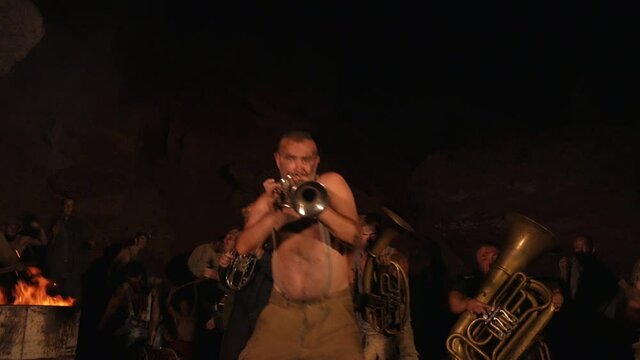 Crazy orchestra playing. Funny musicians play underground in a cave at night. Crazy people play musical instruments and dance funny dances in the cave. Funny bass guitarist, tubist, trumpeter, drummer