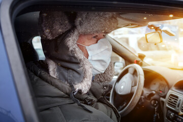 Man is sitting in the passenger seat of a car wearing a protective mask. Daily prevention of infections and viruses. Close-up.