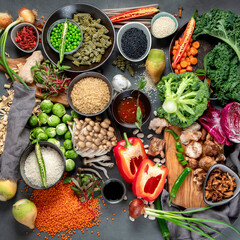 Asian raw vegan food, grain, seeds and vegetables on dark background