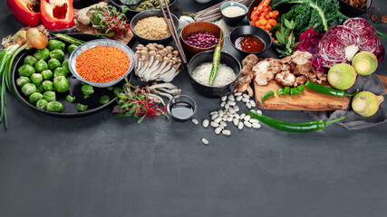 Asian raw vegan food, grain, seeds and vegetables on dark background