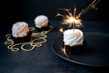 Delicious cupcakes with sparkler on dark background