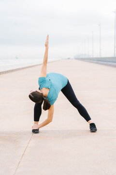 Girl practicing yoga extended triangle pose on the street