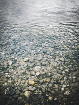 Rippling water and stones and mossy rocks on the bottom of river shore