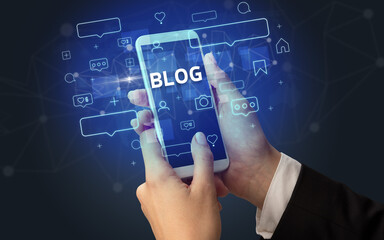 Female hand typing on smartphone with BLOG inscription, social media concept
