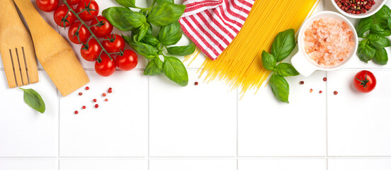 Raw spaghetti with parmesan cheese and tomatoes, basil, garlic and oil on light background with...