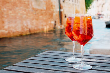 Two glasses of Spritz Veneziano cocktail served near the Venetian canal.  Popular italian summer aperitif drink. Place for text. Venice background.