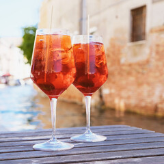 Two glasses of Spritz Veneziano cocktail served near the Venetian canal.  Popular italian summer aperitif drink.
