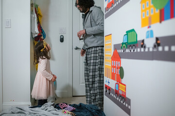 Little girl in tiara looking up at dad in domestic kids bedroom