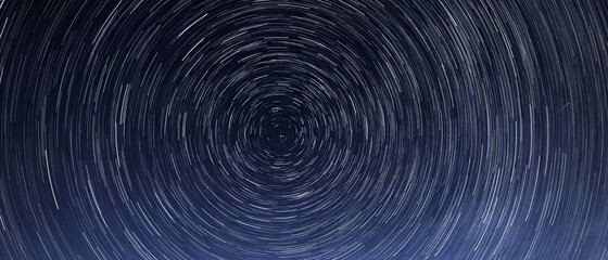 Stellar trails, the rotation of bright stars at night around the Polar Star against a blue sky and a meteor