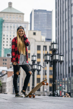 Female millennial in urban area with skateboard ready to roll ar
