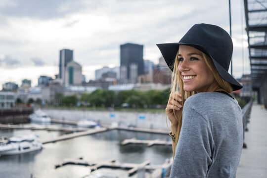 Blonde female with hat on and city skyline behind her