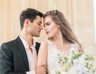 Closeup Portrait of wedding young bride and groom with bouquet posing by the old cathedral. Honeymoon couple kissing at wedding day, happy couple in love, wedding kiss