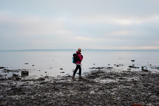woman with a backpack walking along the English coast alone