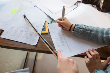 close-up of two children drawing a holiday music program on paper