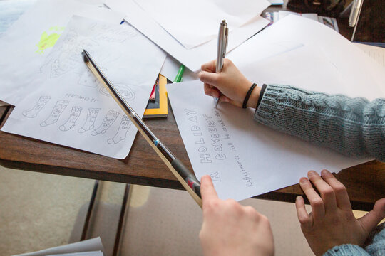 close-up of two children drawing a holiday music program on paper