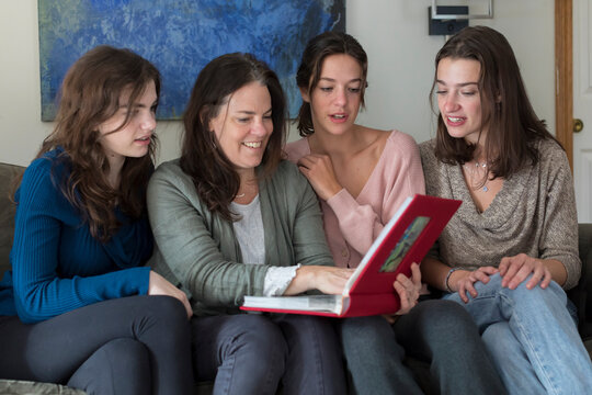 A mother and her three daughters look at a photo album together